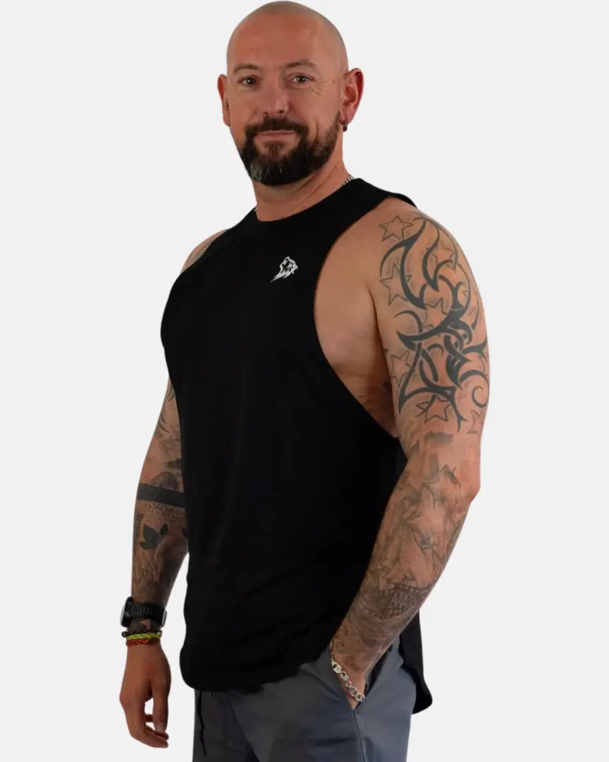 A man with tattoos and a beard standing in front of a white background.