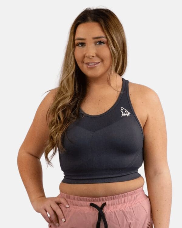 A woman wearing a black sports bra and pink shorts.