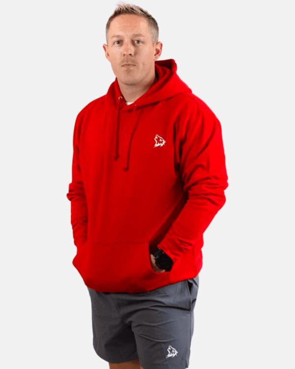 A man wearing a red hoodie with his hands in his pockets.