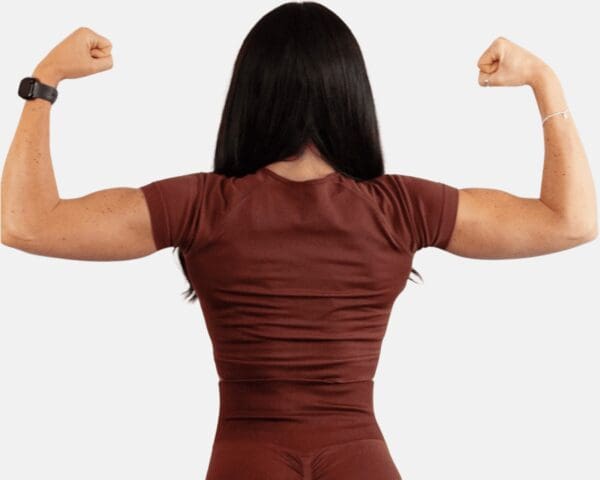 A woman in brown shirt showing her muscles.