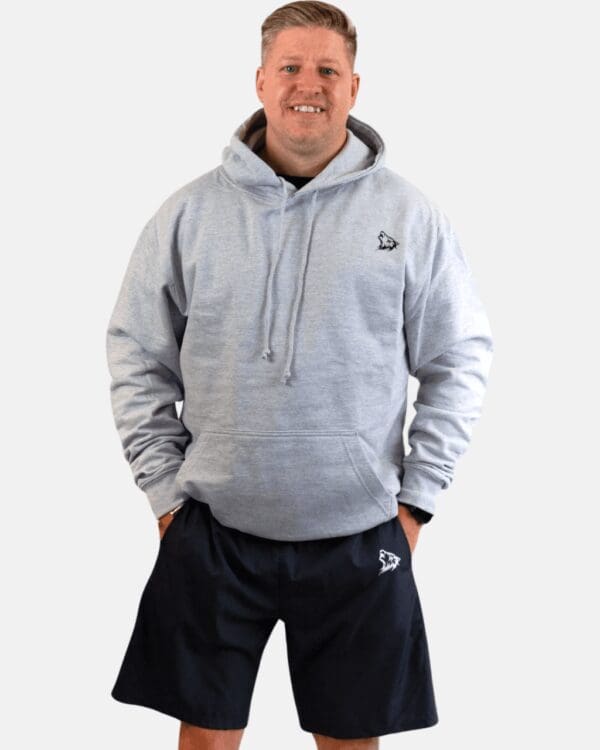 A man wearing a gray hoodie and black shorts.