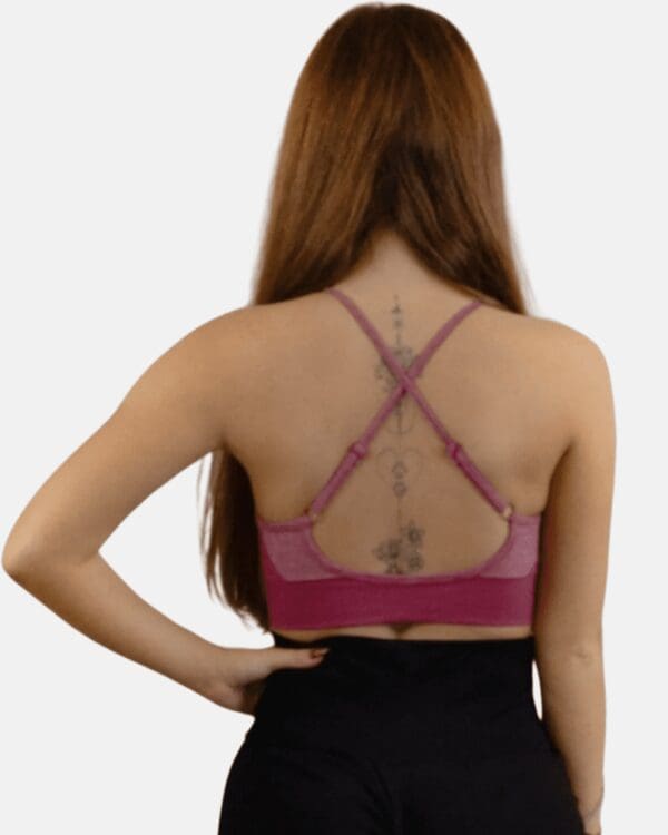 A woman wearing a pink bra with a tattoo on her back.