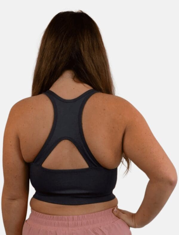 A woman wearing a black sports bra with an open back.