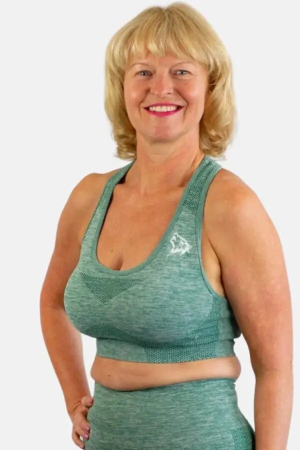 A woman wearing a green sports bra smiling.