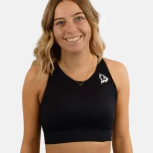 A woman wearing a black sports bra smiling.