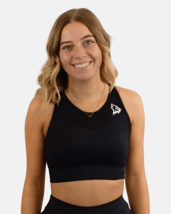 A woman wearing a black sports bra smiling.