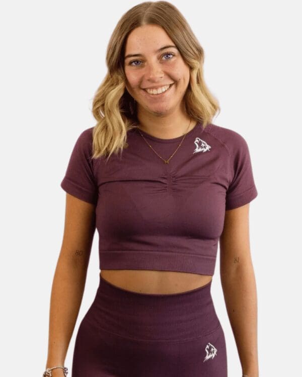 A woman wearing a purple crop top and leggings.