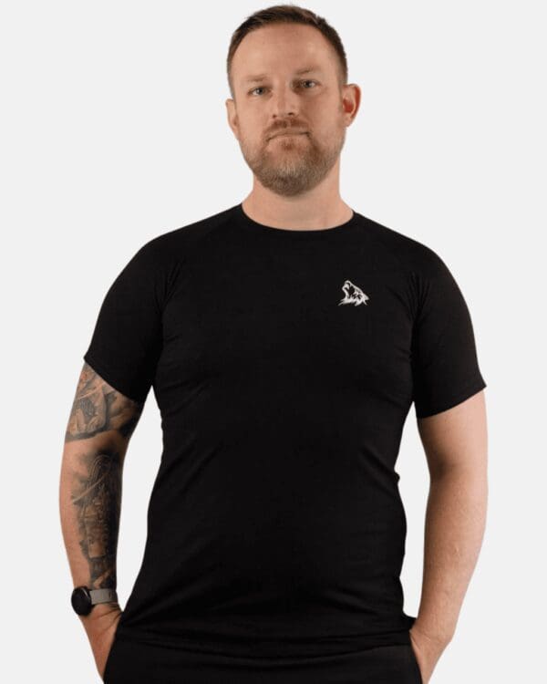 A man with tattoos wearing black shirt and jeans.