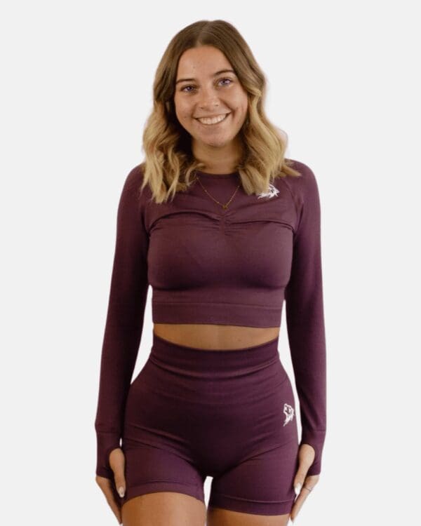 A woman in purple long sleeve top and shorts.