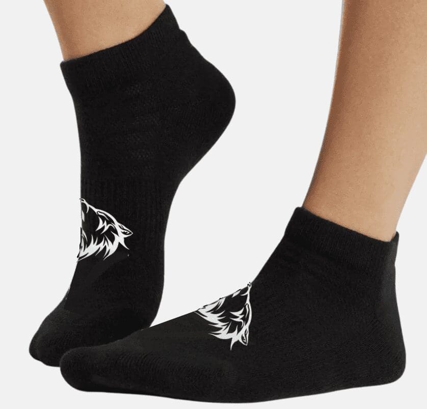 A pair of feet wearing black socks with white wolf on them.