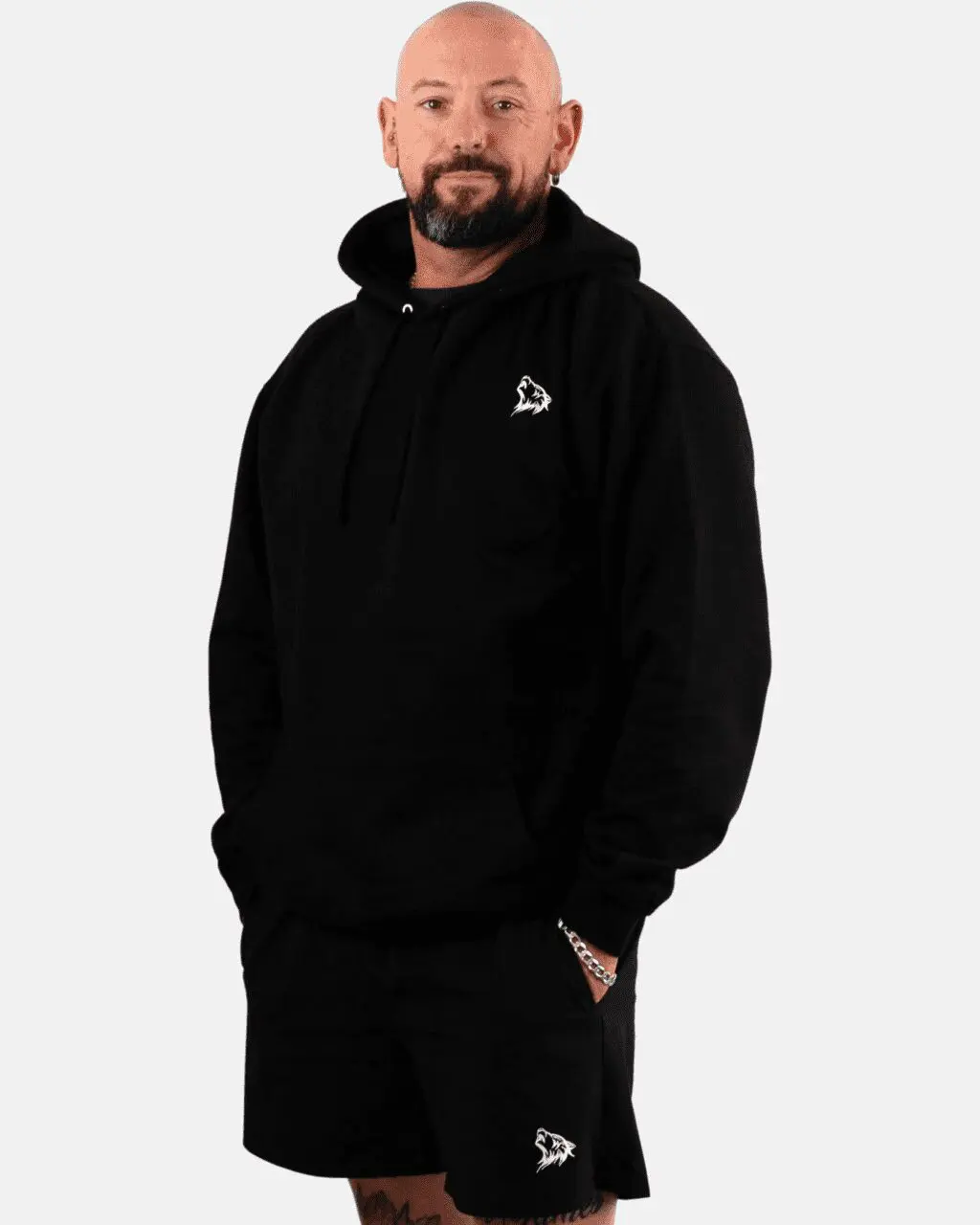 A man in black hoodie standing with his hands in his pockets.
