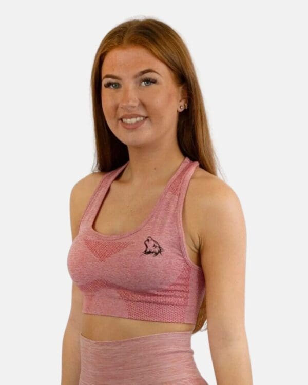 A woman wearing a pink sports bra and leggings.