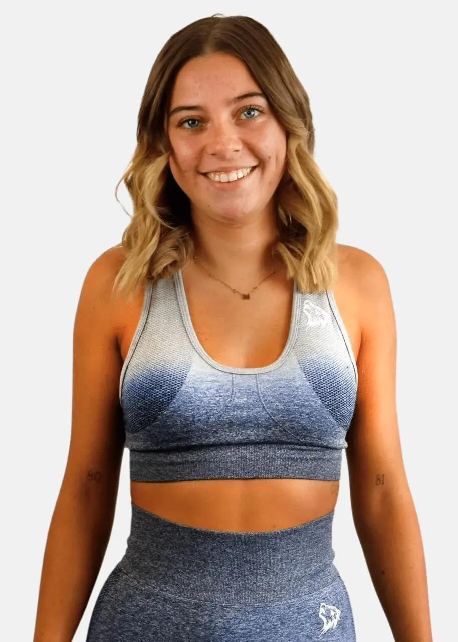A woman wearing a sports bra smiling for the camera.