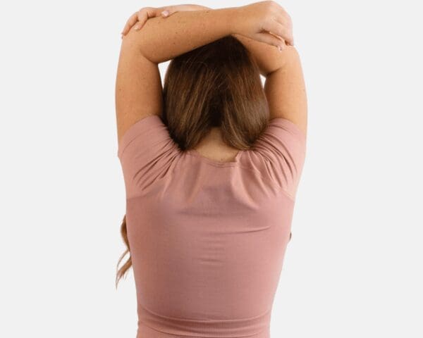 A woman in pink shirt stretching her arms.