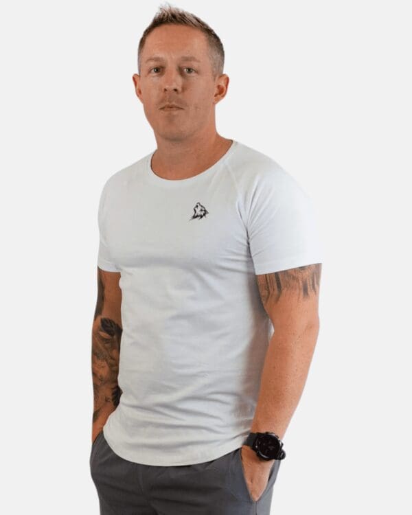 A man with tattoos wearing white shirt and jeans.