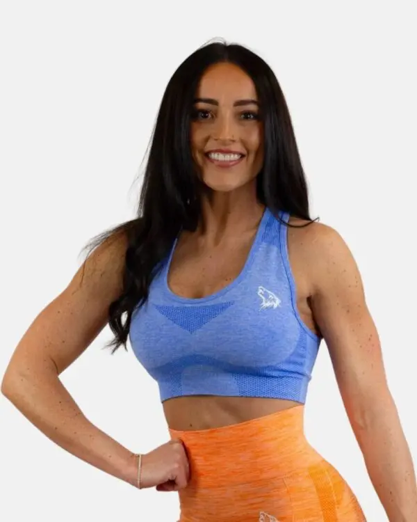 A woman in blue sports bra and orange shorts.