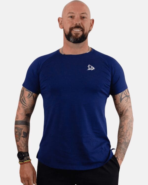 A man with tattoos wearing blue shirt and black pants.