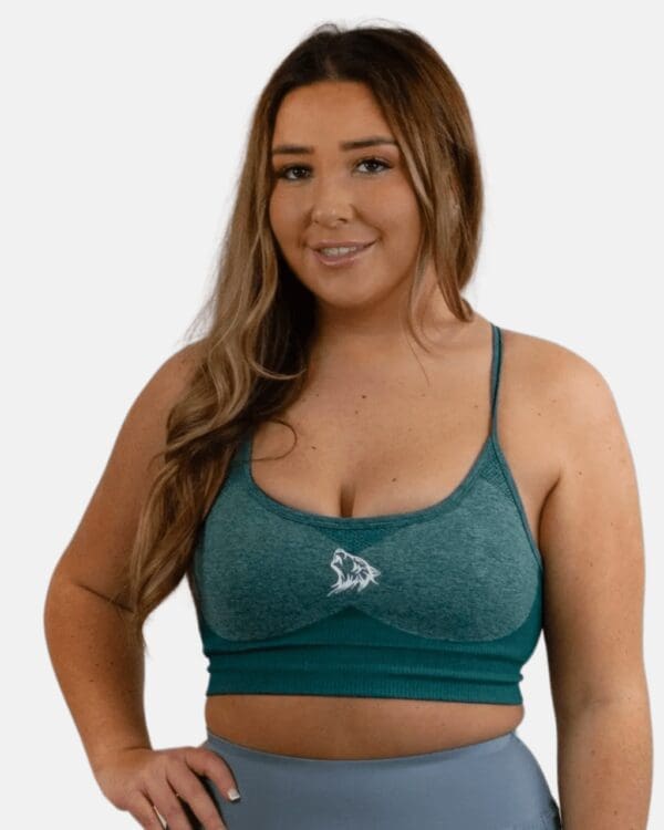 A woman wearing a teal sports bra and jeans.