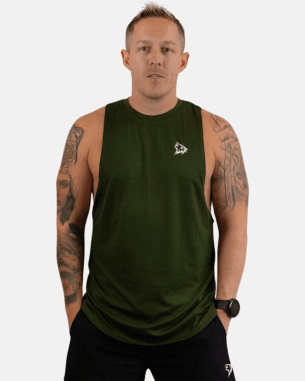 A man wearing a green tank top with his hands in pockets.