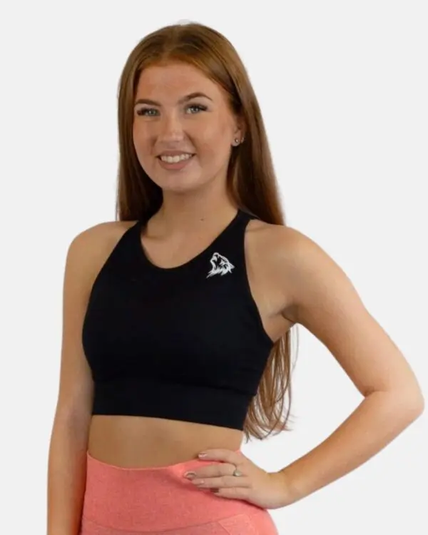 A woman in black sports bra standing next to pink shorts.