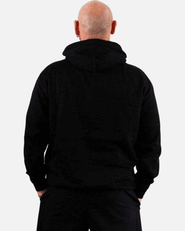 A man wearing black hoodie with his hands in pockets.