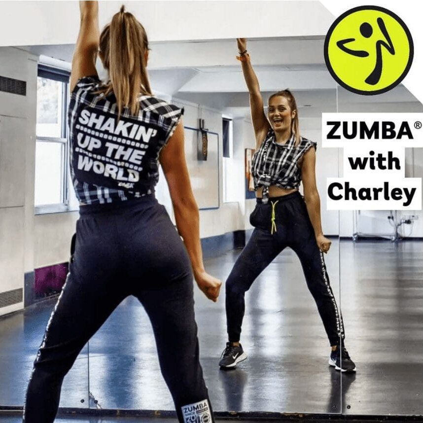A woman is doing zumba with her arms in the air.